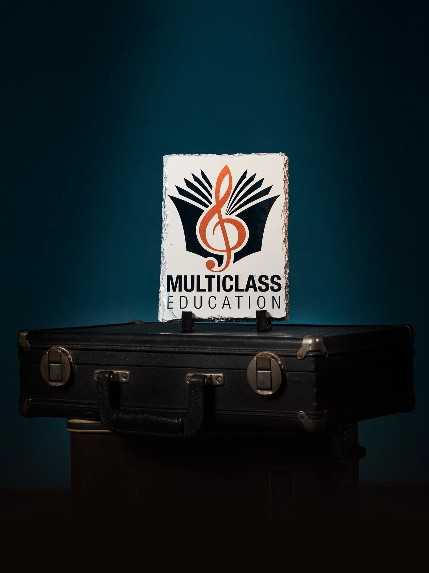 Banner de Multiclass Education. Presenta el logotipo de la academia musical Multiclass Education sobre maletines de instrumenros musicales. 